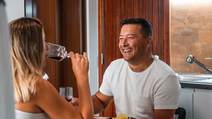 Een man en een vrouw zitten aan een tafel met een schaal chips en een glas rode wijn.