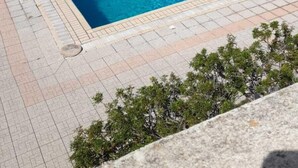 Ein Swimmingpool mit weißen Liegestühlen und einer Steinterrasse.