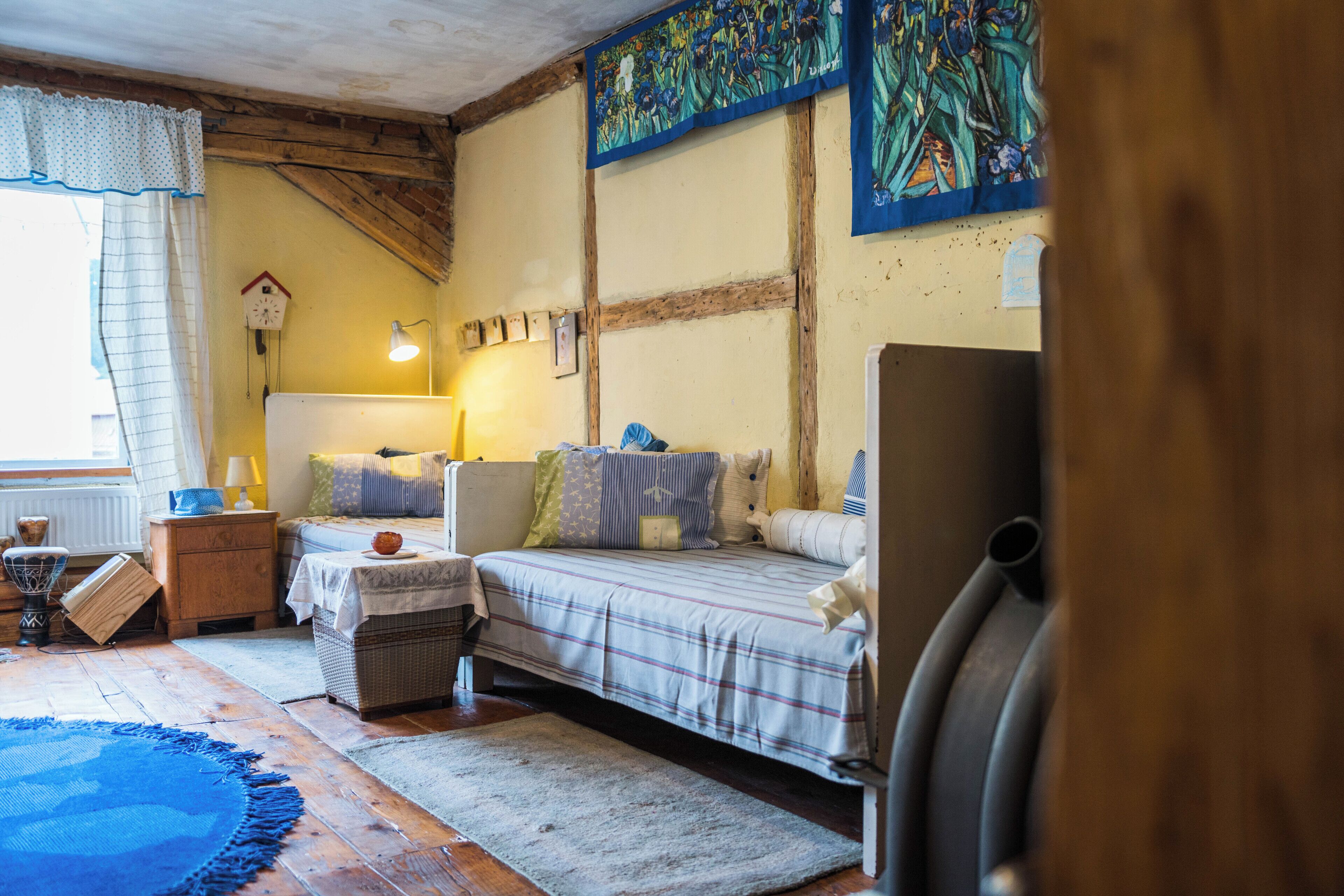 A cozy bedroom with a bed, bedside table, lamp, and a wall clock.