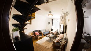 A cozy living room with a wooden staircase, a sofa, a small table, and a decorative wall piece. - Dům v Centru (Ceska Kamenice)