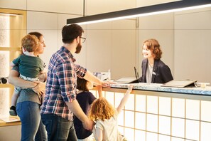 A family interacting with a staff member at a reception desk in a modern hotel lobby. - MIMARU Tokyo Nihombashi Suitengumae (Tokyo)
