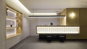 Una moderna area reception di un hotel con un lungo bancone, scaffali con asciugamani e un design minimalista.