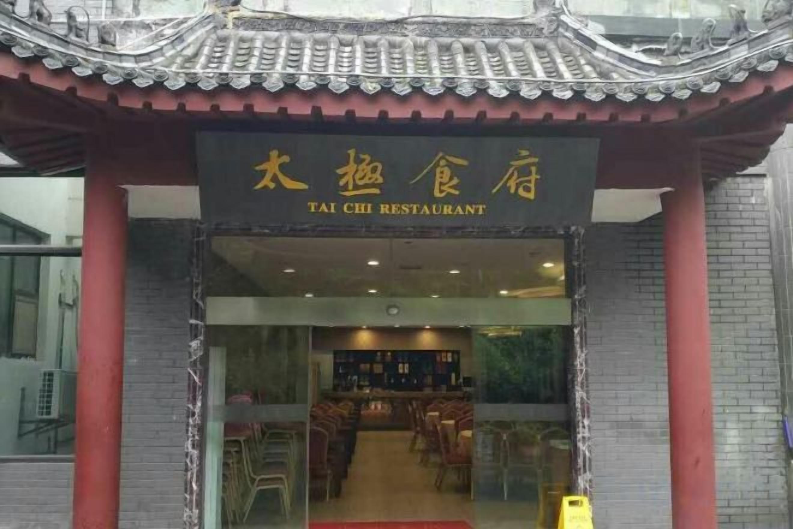 The entrance to a restaurant with a traditional tiled roof and a sign in both Chinese and English.