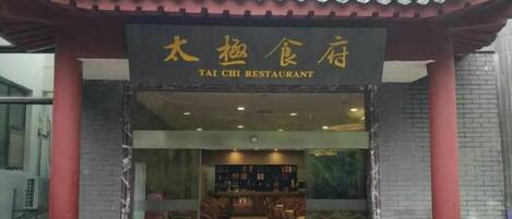 The entrance to a restaurant with a traditional tiled roof and a sign in both Chinese and English.