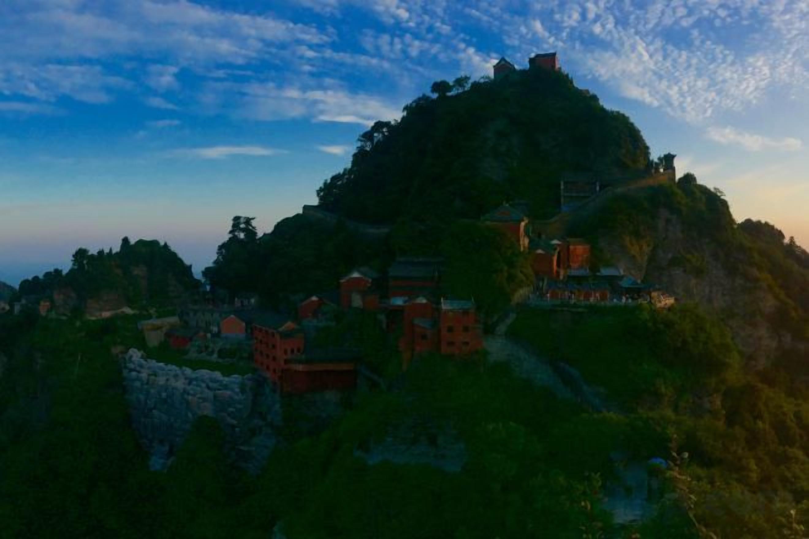 A mountainous landscape with traditional buildings, possibly a historical site or cultural landmark.
