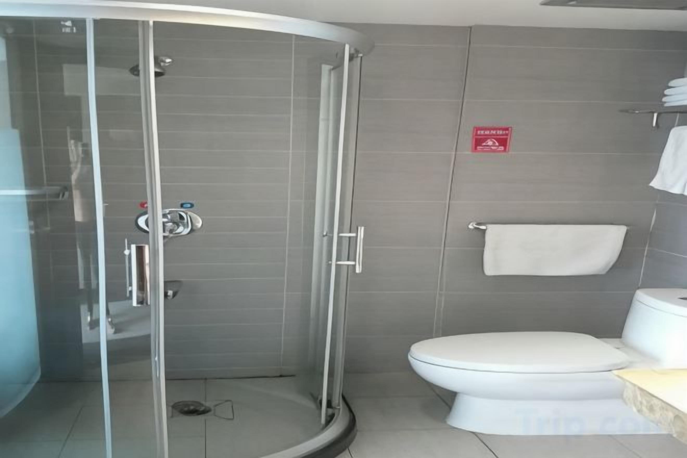 A modern bathroom with a glass-enclosed shower, a toilet, and a towel rack.
