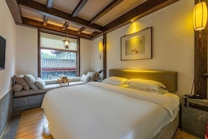 A bedroom with a large bed, a window seat, a bedside table, and a wall-mounted lamp. - Tai Chi Hotel (Shiyan)