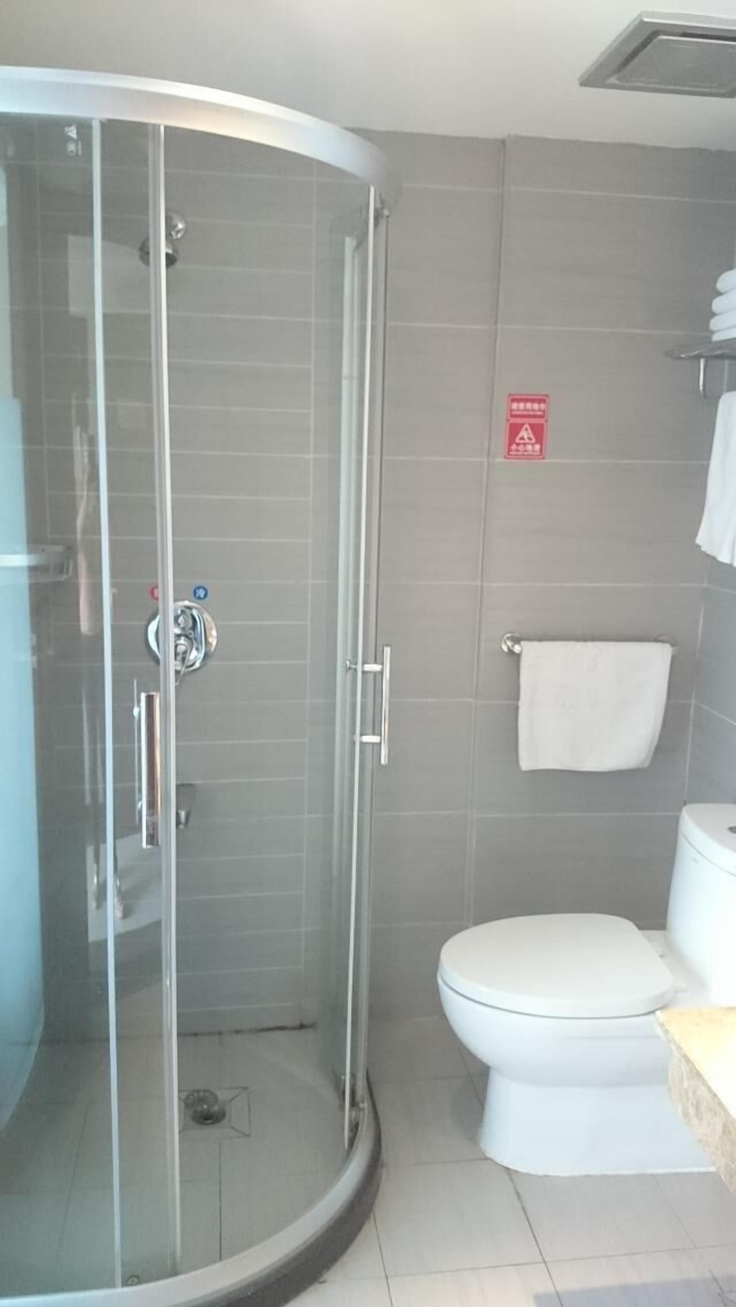 Une salle de bain avec une douche à parois de verre, des toilettes et un porte-serviettes.