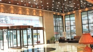 A lobby with a revolving door, large windows, a reception desk, and a seating area. - Tai Chi Hotel (Shiyan)