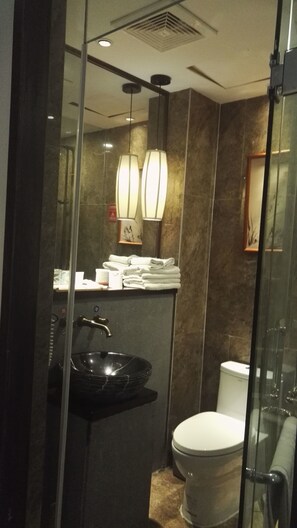 A modern bathroom with a glass shower enclosure, a black sink, and a toilet. - Tai Chi Hotel (Shiyan)