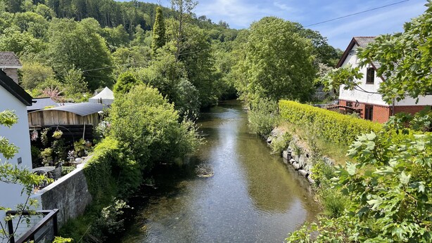 A narrow river flanked by lush greenery and traditional buildings. - Cottage In Dôl Y Bont, Near Aberystwyth, Ceredigion, Wales. (Dol y bont)
