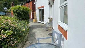 A residential property with a white exterior, a brick chimney, and a garden with flowering plants. - Cottage In Dôl Y Bont, Near Aberystwyth, Ceredigion, Wales. (Dol y bont)