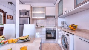 Cocina compacta con refrigerador, microondas, horno y lavadora.