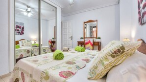 Un dormitorio con cama, espejo, puerta y ventilador de techo.