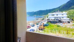 A view from a window overlooking a coastal area with a white building, parked cars, and a construction site. - Two Fish (Lanyu)