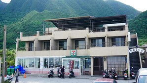 A 7-Eleven convenience store with a mountain backdrop. - Two Fish (Lanyu)