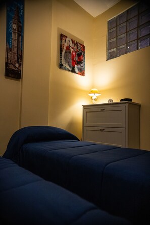 Ein Schlafzimmer mit einem Bett, einem Nachttisch mit Lampe, einer Wanduhr und zwei Bildern.