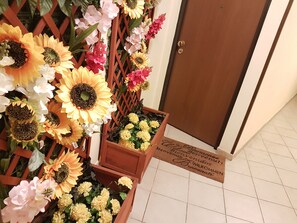 A wooden door with a welcome mat and a decorative arrangement of sunflowers and flowers.