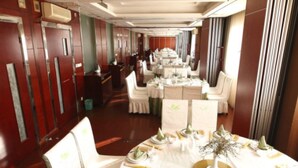 A formal dining room with round tables, white chairs, and a central floral arrangement. - Kunshan Yuxing Hotel (Suzhou)