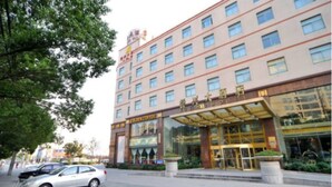 A hotel with a modern facade, multiple floors, and a prominent entrance with glass doors. - Kunshan Yuxing Hotel (Suzhou)