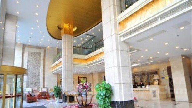 A spacious lobby with a high ceiling, multiple floors, and a central column. - Kunshan Yuxing Hotel (Suzhou)