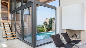 Een modern interieur met een glazen deur naar een zwembad, een open haard en een trap met houten treden.