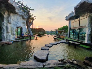 A serene riverside setting with a wooden walkway, outdoor seating, and a view of the sunset. - I View Park Resort (Udon Thani)