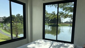 Una camera da letto con un'ampia finestra che si affaccia su un lago e alberi.