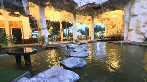 Un giardino roccioso interno con elemento d'acqua, zone relax e area ristorazione.