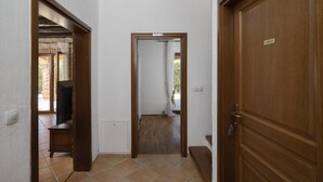 A hallway with a wooden door labeled 'PRIVATE,' a television in a corner, and a tiled floor.