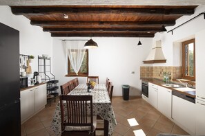 A kitchen with a dining table, chairs, a hanging light fixture, a window with curtains, and a tiled backsplash. - Villa Orlene in Paradis (Svetvinčenat)