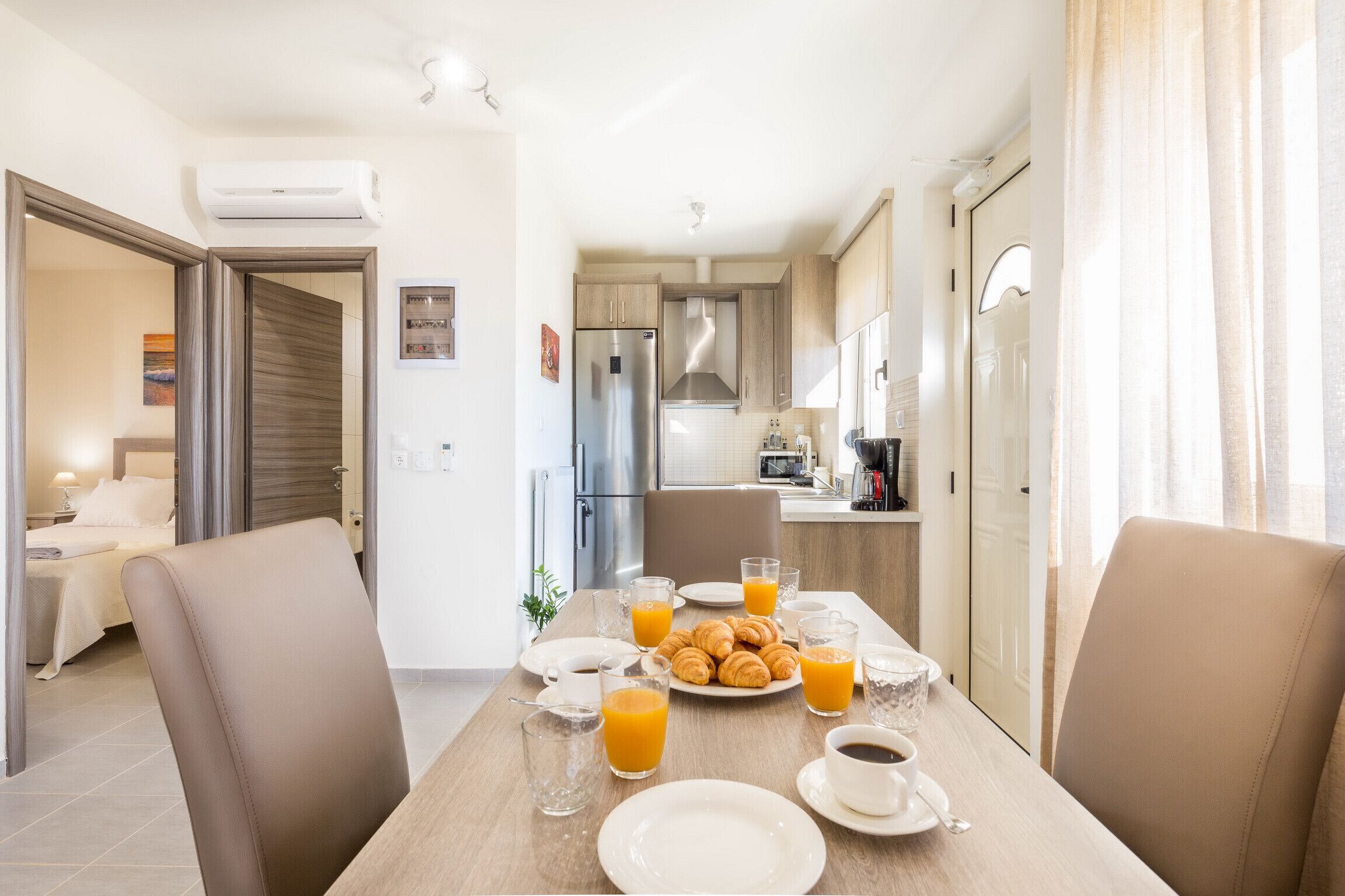 Una cocina moderna con comedor, que incluye un desayuno con cruasanes, jugo de naranja y café.