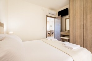 Una habitación de hotel con una cama, un armario de madera, un espejo y un escritorio con una silla.