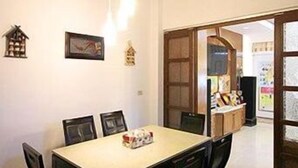 A dining area with a table and chairs, a hanging light fixture, and a doorway leading to another room. - Tomato Coffee BnB (Taitung)