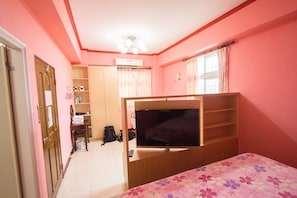 A bedroom with a bed, a TV, a wardrobe, a desk, and a window with curtains. - Tomato Coffee BnB (Taitung)