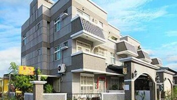 A multi-story building with a modern architectural design, featuring a flat roof, large windows, and a prominent entrance with a decorative archway. - Tomato Coffee BnB (Taitung)