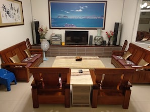 A living room with a TV, sofa, coffee table, and decorative items. - Sea Bay B&B (Taitung)