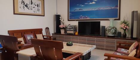 Un salón con televisor, muebles de madera y un cuadro grande.