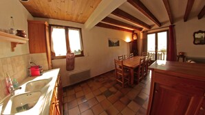 A kitchen with wooden beams, a dining table, and a large window.
