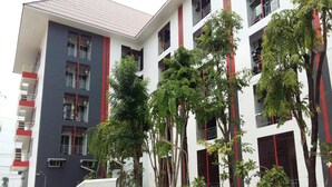 Un edificio de varios pisos con balcones y un área de estacionamiento.