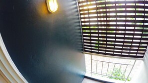 Una habitación con pared oscura, una lámpara y una ventana con persianas.