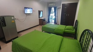Habitación de hotel con dos camas individuales, un escritorio con silla, televisión en la pared y un armario.