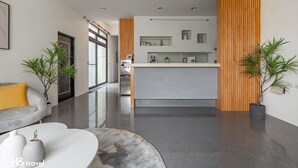 Een moderne hotellobby met een receptiebalie, een bank en potplanten.