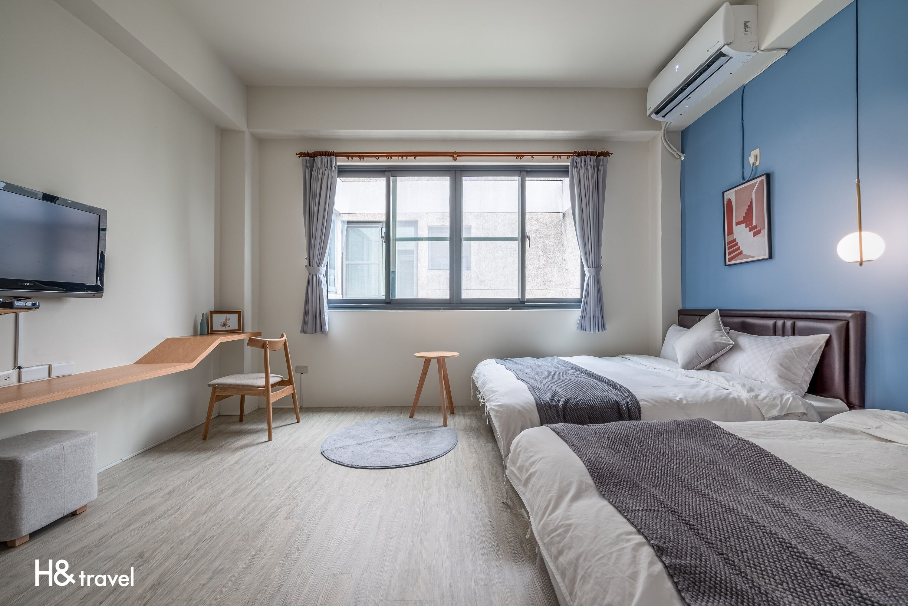 Una habitación de hotel con una cama, un escritorio, una silla, un tapete redondo y un televisor.