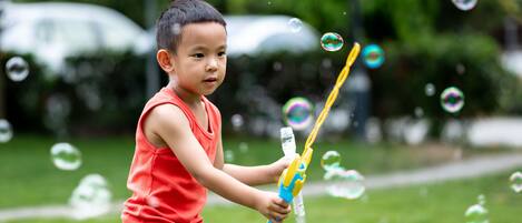 Un niño jugando con burbujas en un parque.