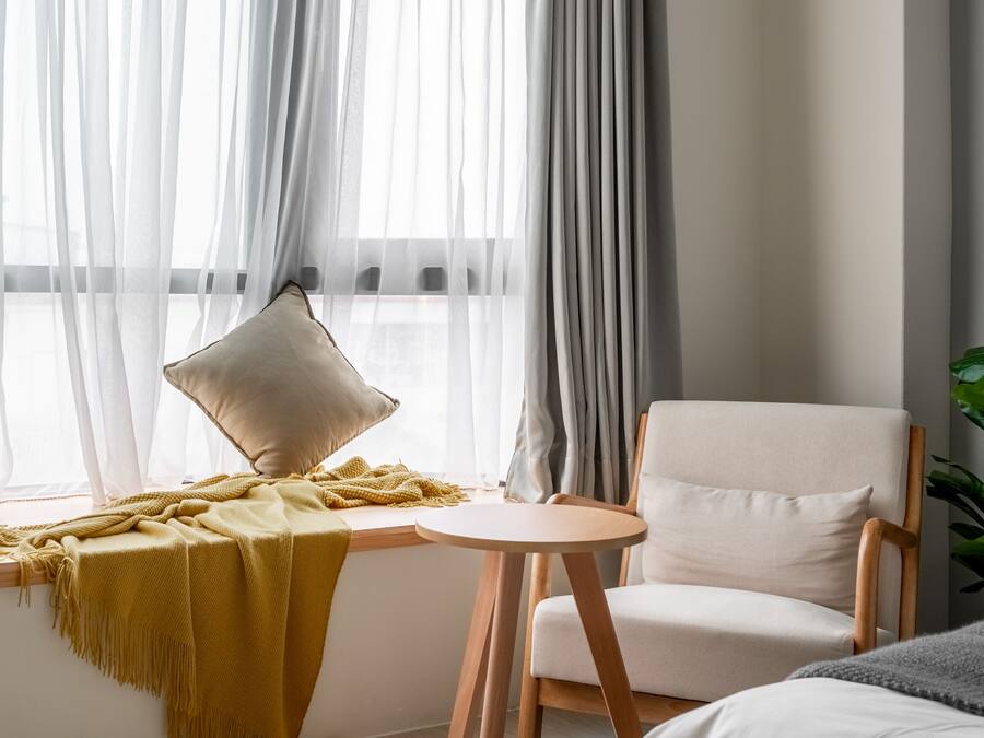 A room with a window, a chair, a small table, and a plant.