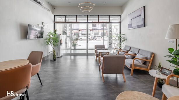 Een moderne hotel lobby met een groot raam, zithoek en een wandgemonteerde televisie.