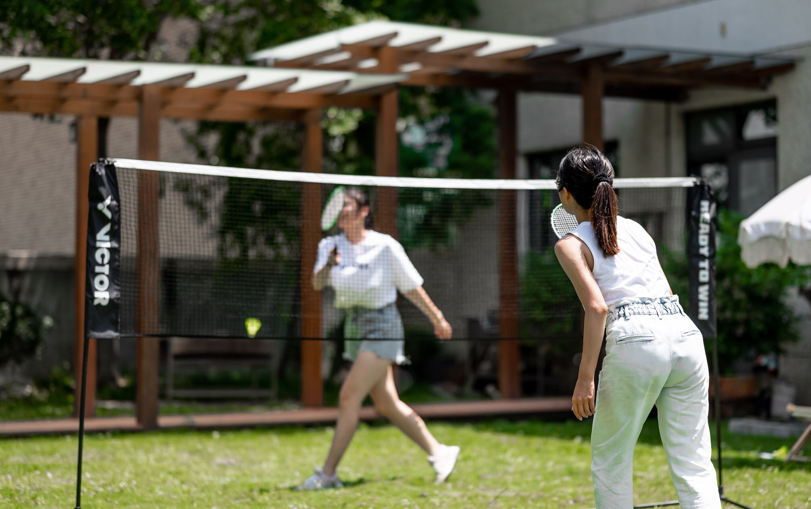 An outdoor tennis court with a net labeled "VICTOR".