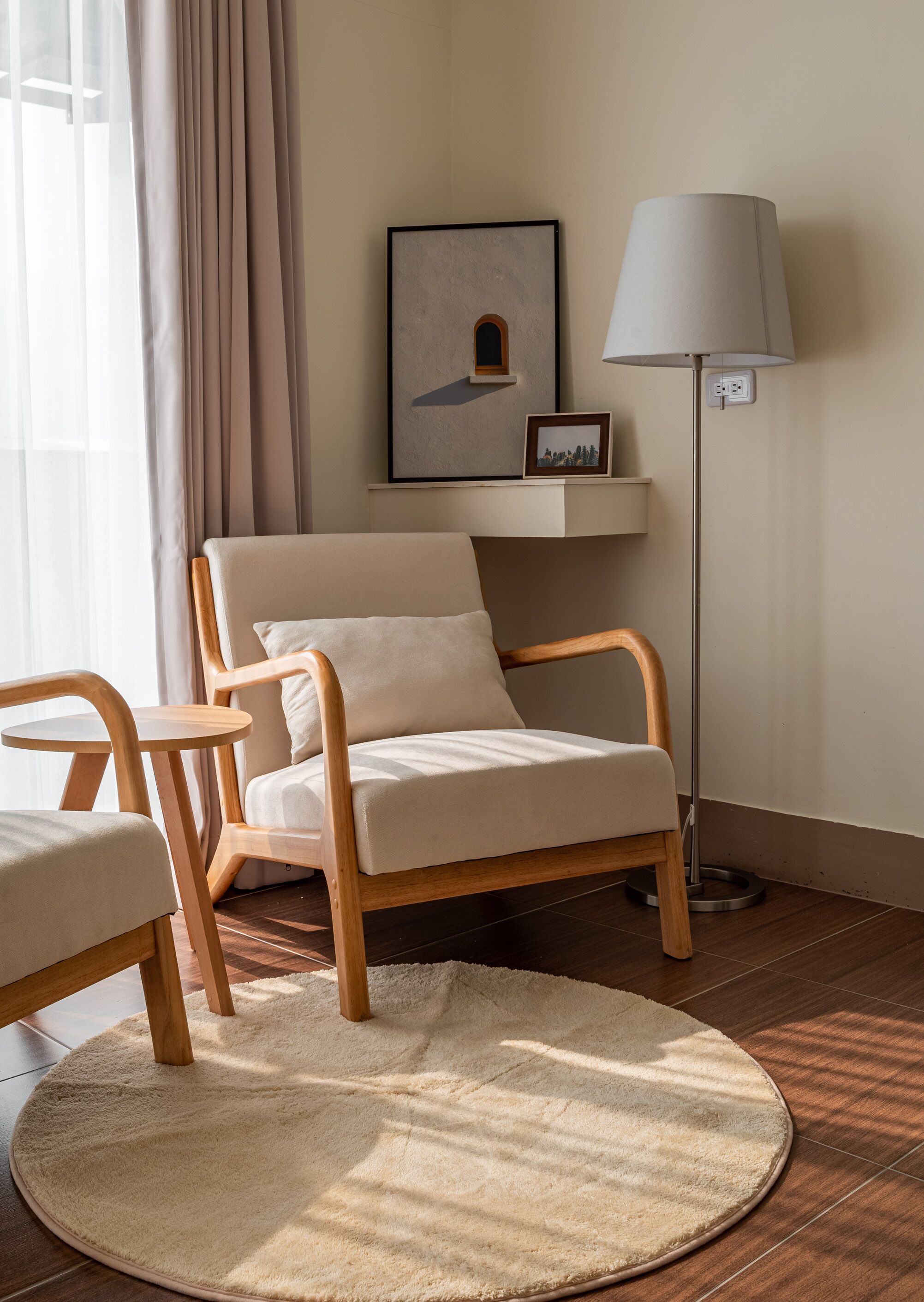 A modern room with a wooden chair and a small table, a floor lamp, and a framed picture on the wall.