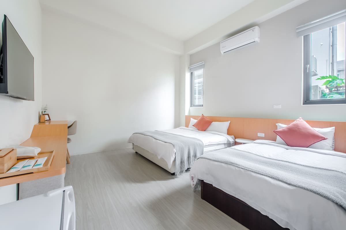 A hotel room with two beds, a desk, and a TV.